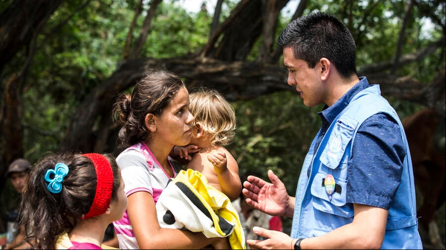 Una mujer con dos niños pequeños charla con un trabajador de ACNUR en Colombia. Una mujer con dos niños pequeños charla con un trabajador de ACNUR en Colombia.