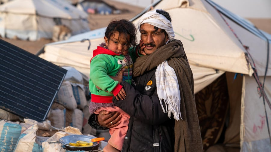 Un hombre sostiene a un niño en brazos en un campamento de refugiados